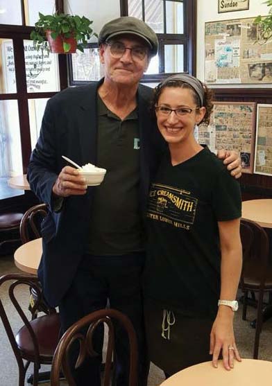 James Taylor got a taste of the Ice Creamsmith’s banana flavored goodness during a surprise visit to the Lower Mills shop on Monday. He is shown with co-owner Sarah Mabel-Skillin. Photo courtesy Ice Creamsmith